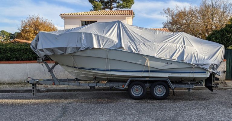 boat on a trailer with a grey tarp cover - 247 Self Storage boat storage